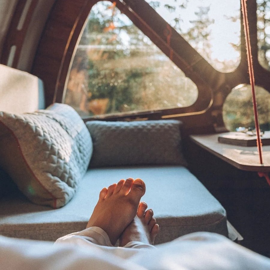 Looking out through the cabin’s round windows from a cushioned window seat, with a guest’s feet up.