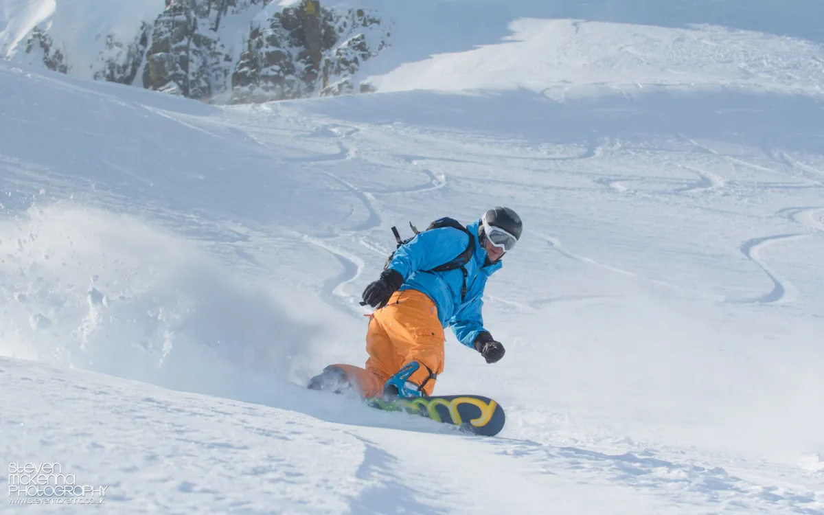 Chris snowboarding through fresh powder.