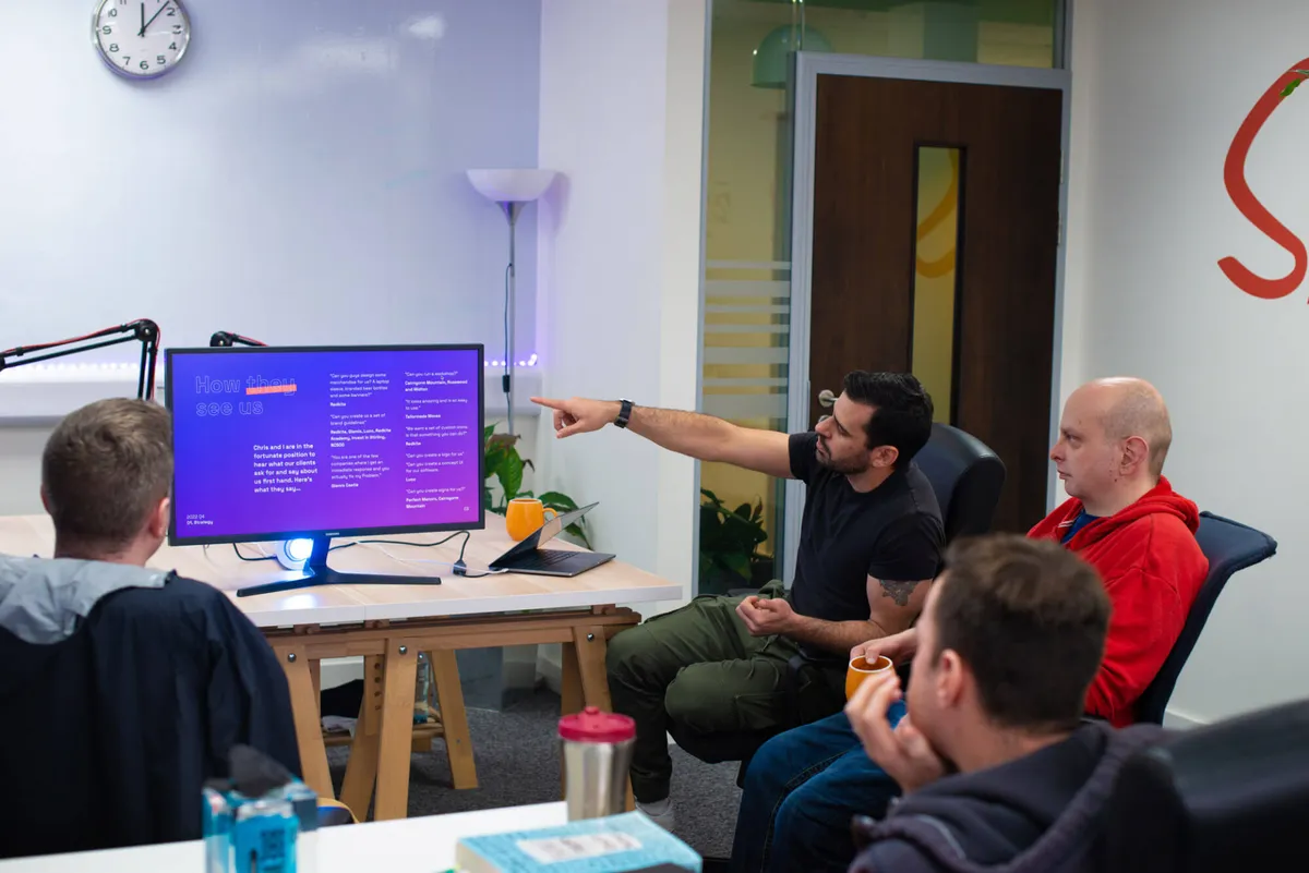 Ed pointing out a design on a big screen to the Strut team in the studio.