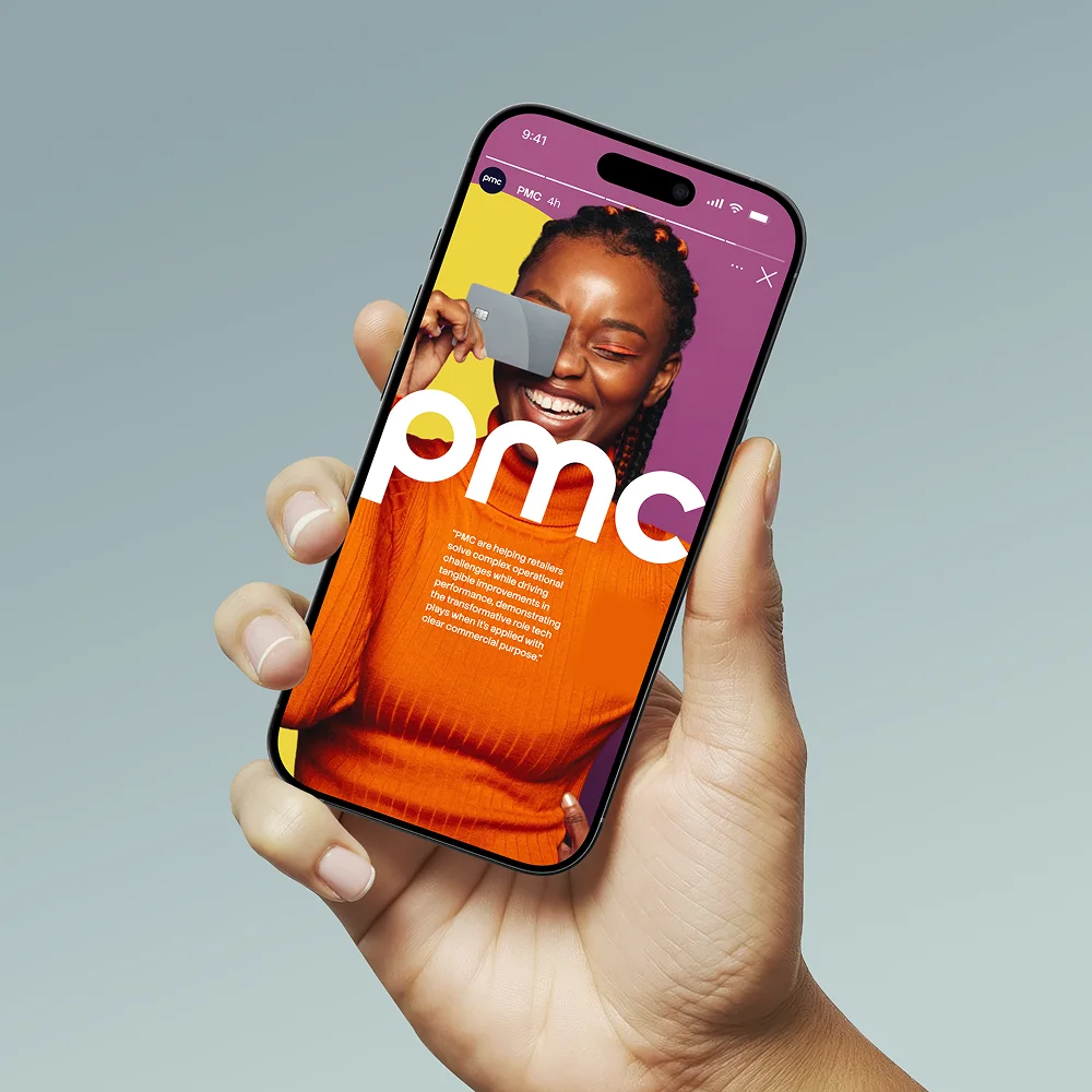 A hand holding a phone showing the PMC brand imagery.