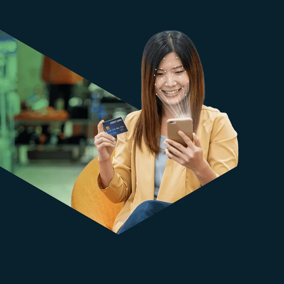 A woman in a yellow jacket smiles at her phone while holding a bank card, set in an angled Primrose frame.