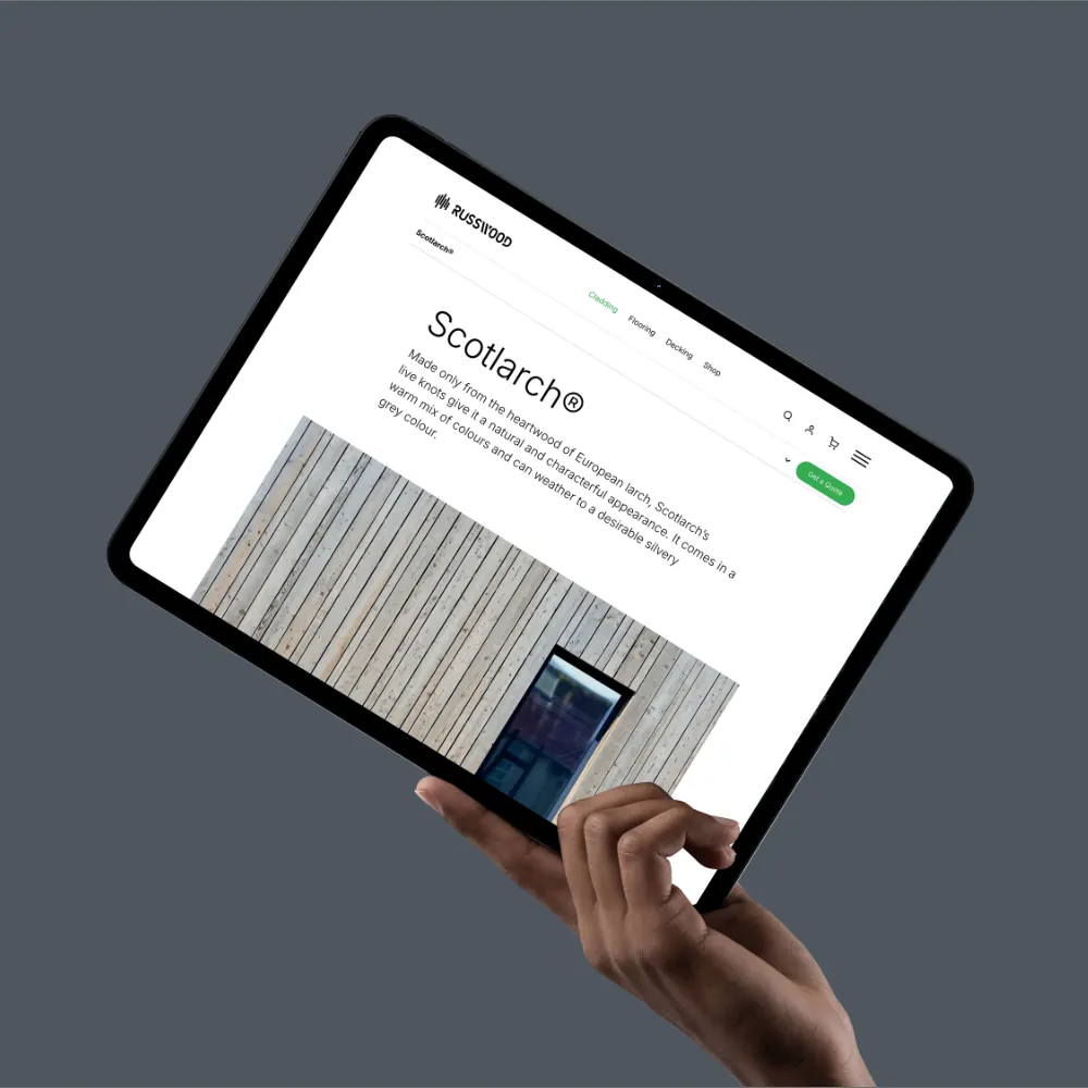 A hand holding a tablet showing the Russwood website’s Scotlarch cladding page.