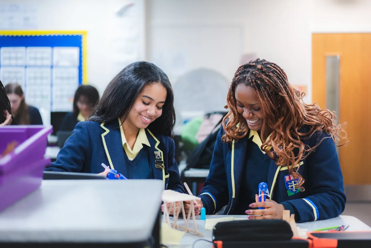 Two pupils in blazers working together in a classroom.