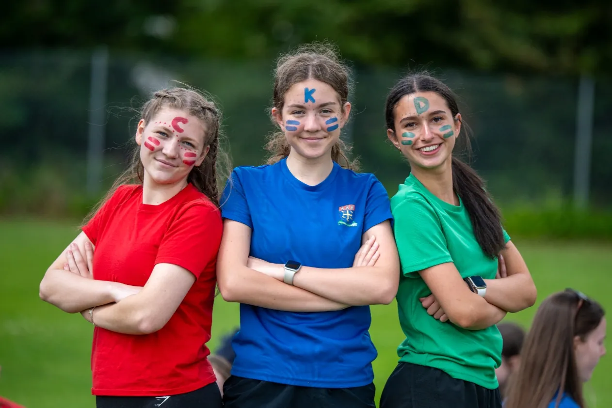 Three pupils with painted faces on the playing field on sports day.