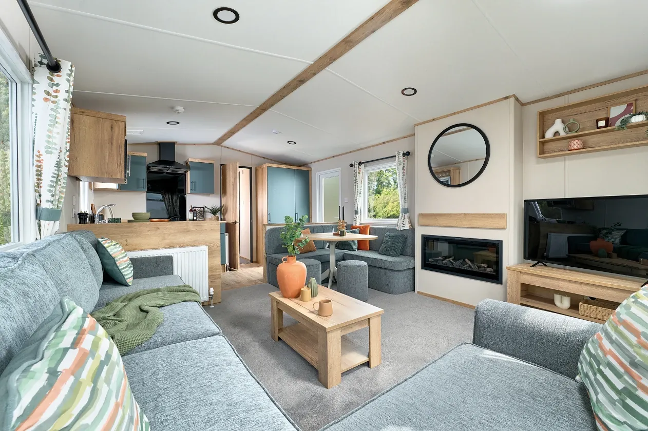 The living area of a two-bed caravan, with a corner sofa and a fireplace.